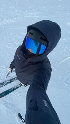 a person wearing skis and goggles in the snow with one hand on their hip