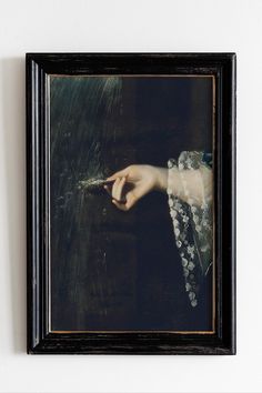 a framed photograph of a woman's hand holding something