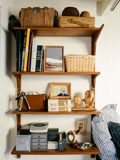 some shelves with books, pictures and other items on them in a room that has white walls