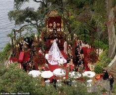 an aerial view of a wedding ceremony on the water's edge with red carpet and white umbrellas