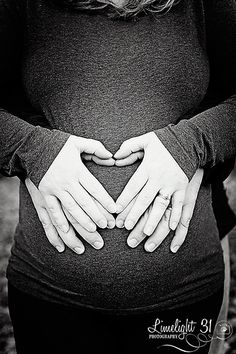 a pregnant woman holding her hands in the shape of a heart