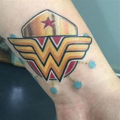 a wonder woman tattoo on the left arm and wrist with stars in it, as well as an emblem