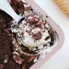 a scoop of ice cream in a pink container with chocolate chunks and powdered sugar