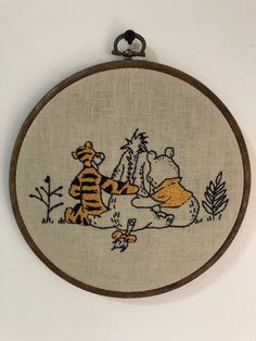 a cross stitched picture of winnie the pooh and tigger on a wall