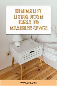 a white nightstand sitting on top of a wooden floor next to a bed with pillows