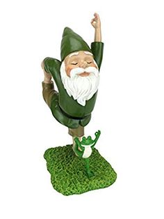 a garden gnome figurine is posed on top of a green patch of grass