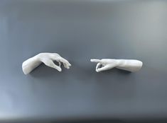 two white hands reaching towards each other on a gray surface with one hand pointing at the other