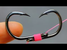 a fishing hook with two claws sticking out of it's mouth and pink string