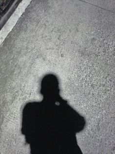 the shadow of a person standing next to a street