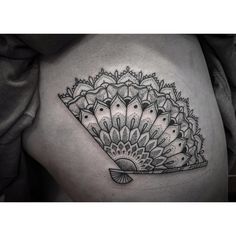 a black and white photo of a woman's thigh with a fan tattoo on it