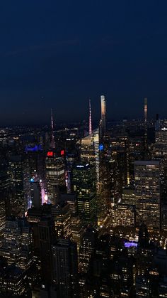 an aerial view of the city at night with skyscrapers lit up in red, white and blue