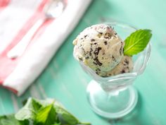 two scoops of ice cream sit in a small glass bowl on a green table