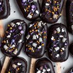 chocolate covered donuts with sprinkles and toppings on wooden spoons