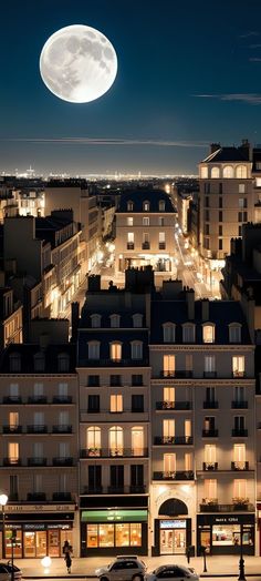 the full moon is seen over an urban area at night, with cars parked on the street