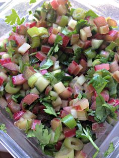 a glass bowl filled with chopped vegetables on top of a table