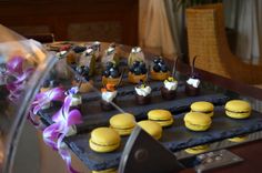 an assortment of desserts are displayed on a tray with purple flowers in the foreground