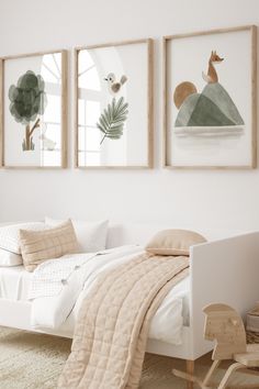 three framed pictures hang on the wall above a bed in a room with white walls