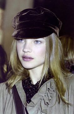 a woman with blue eyes wearing a brown hat and coat, looking at the camera