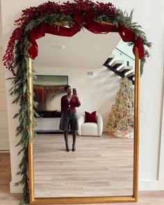 a woman taking a selfie in front of a mirror with christmas decorations on it