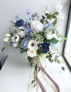 a bouquet of white and blue flowers sitting on a window sill in front of a mirror