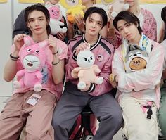 group of young men sitting next to each other holding stuffed animals