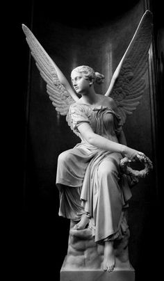 a statue of an angel sitting on top of a stone slab with wings outstretched in front of a black background