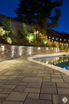 an outdoor swimming pool surrounded by landscaping lights