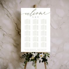 a wedding seating chart on a easel with flowers and greenery next to it