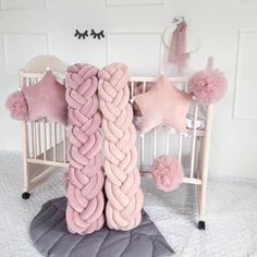 a pink and grey crib with two large braid pillows