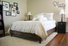 a bedroom with white bedding and pictures on the wall