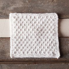 a white knitted dishcloth sitting on top of a wooden table