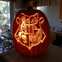 a carved pumpkin with hogwarts crest on it