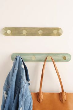 a handbag and coat hanger on a white wall next to a denim jacket