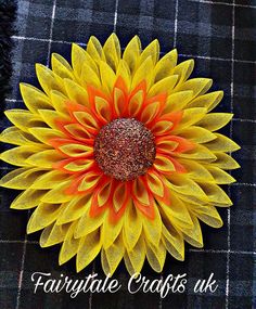 a yellow and orange flower with the words fairytale crafts uk on it's side