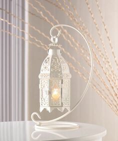 a white lantern on a table with some branches in the background