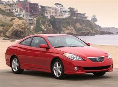 a red car is parked on the beach