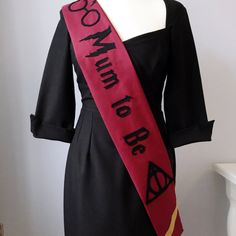 a woman wearing a black dress with a red sash around her neck and words on it