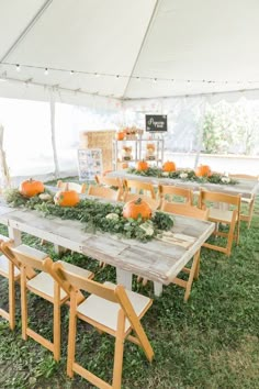 an outdoor table set up with pumpkins and greenery on it for a wedding reception