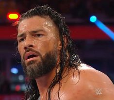 a man with long hair and beard standing in front of a crowd at a wrestling match