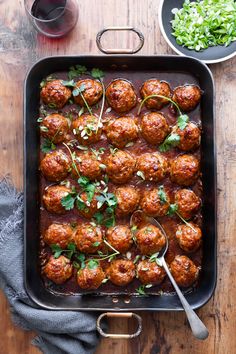 meatballs covered in marinara sauce and garnished with parsley on a wooden table