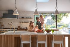 a woman and two children are in the kitchen with their mother on the counter top