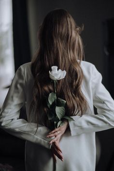 a woman with long hair holding a white rose