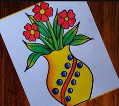 a yellow vase filled with red flowers on top of a wooden table next to a piece of paper