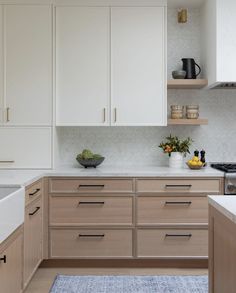 a kitchen with wooden cabinets and white counter tops, along with a blue rug on the floor