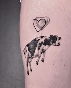 a black and white cow with a heart shaped balloon on it's back leg