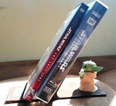 two star wars books are sitting on a table with a baby yoda figurine