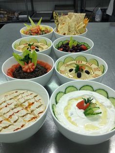 a table topped with bowls filled with different types of food and dips on top of it