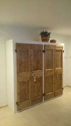 an empty room with two wooden doors and a potted plant on the top shelf