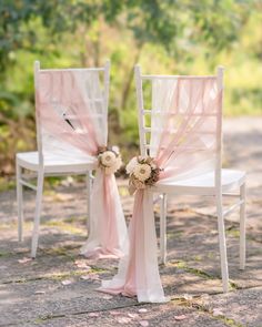 two white chairs with pink sashes and flowers on them are sitting side by side