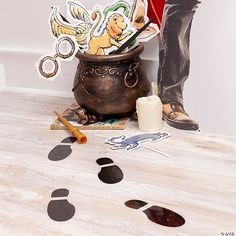 a person standing next to a pot filled with paper cutouts and scissors on top of a wooden floor